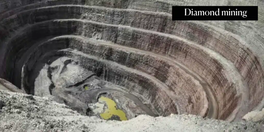 A large open-pit diamond mine showcasing terraced excavation levels and a pool of water at the bottom, illustrating At What Depth is Diamond Found in open-pit mining techniques.