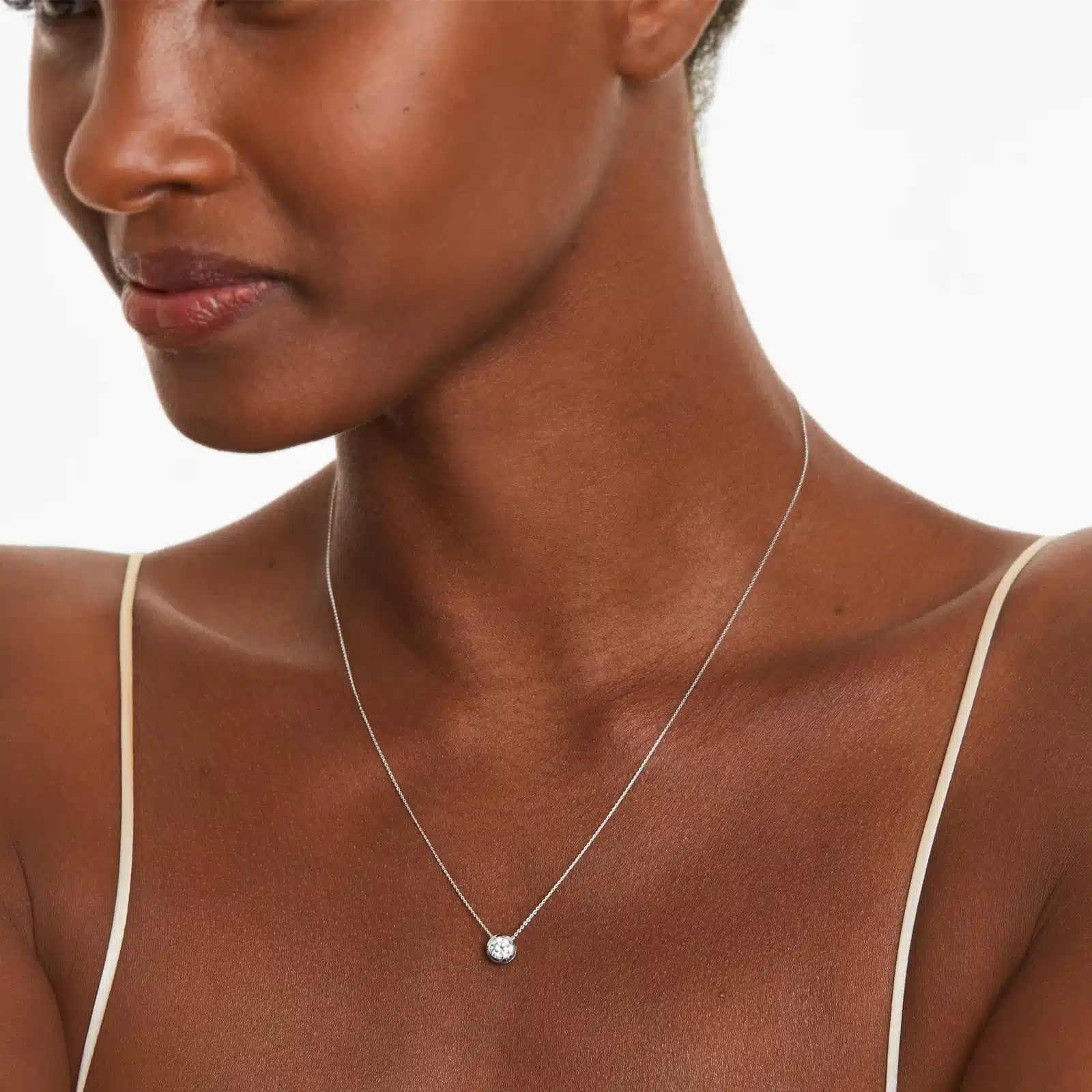 A 0.50 CTW diamond appears to float in a secure 14K white gold bezel setting. Adjustable 16-18" chain.