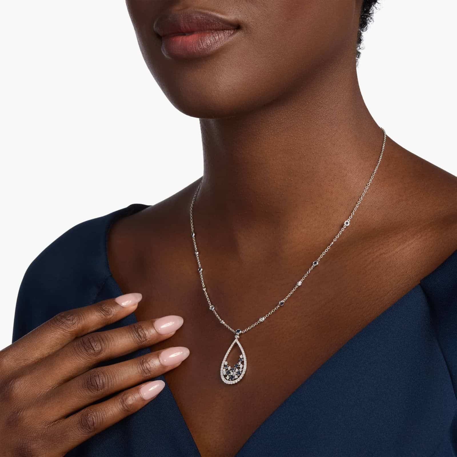 An intricate floral teardrop pendant crafted with deep blue sapphires and brilliant diamonds, hanging from a delicate 18k white gold cable chain.