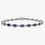 A captivating tennis-style bracelet featuring twenty vibrant blue oval sapphires elegantly alternating with brilliant round diamonds in a sleek 18k white gold setting.