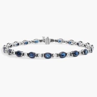 A captivating tennis-style bracelet featuring twenty vibrant blue oval sapphires elegantly alternating with brilliant round diamonds in a sleek 18k white gold setting.