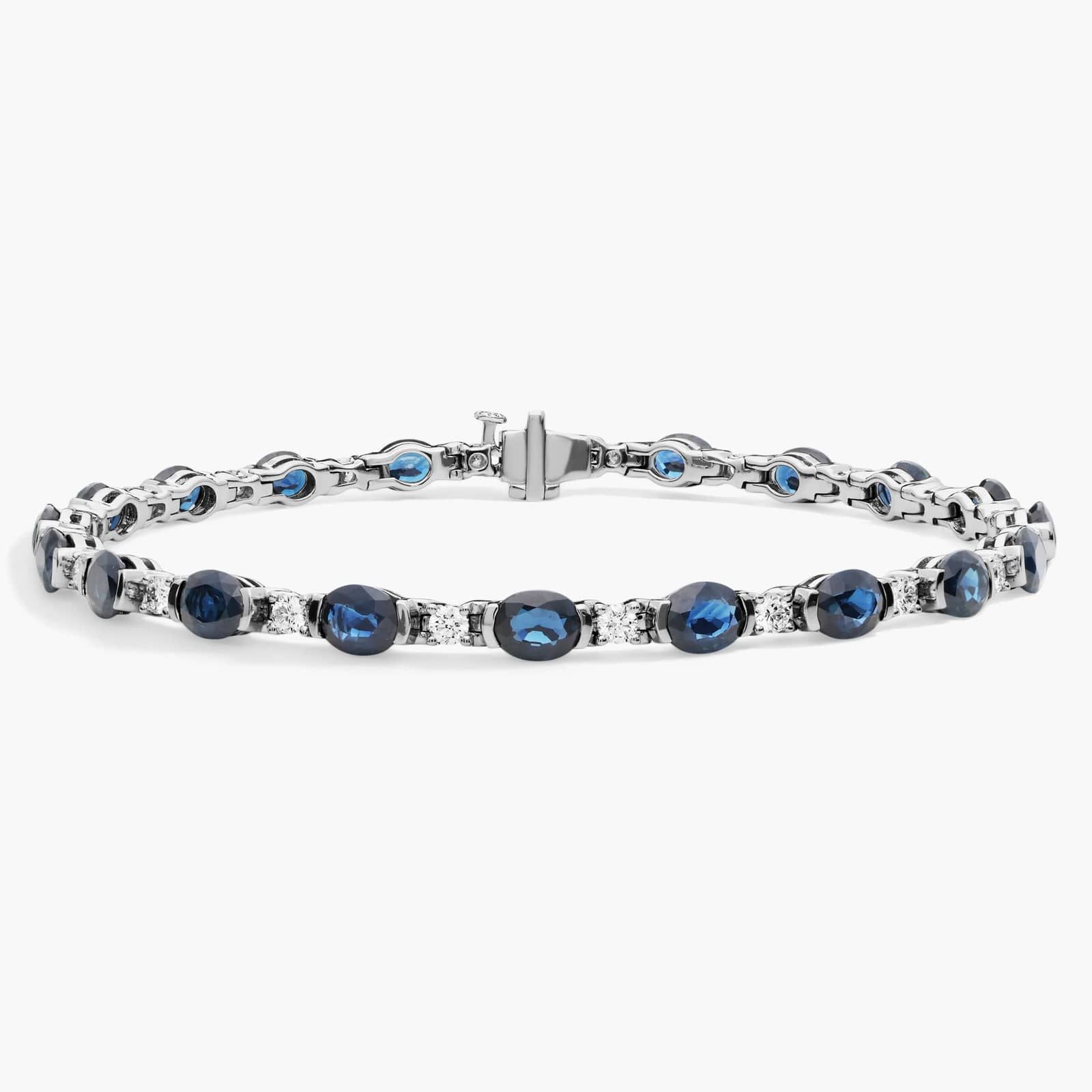 A captivating tennis-style bracelet featuring twenty vibrant blue oval sapphires elegantly alternating with brilliant round diamonds in a sleek 18k white gold setting.