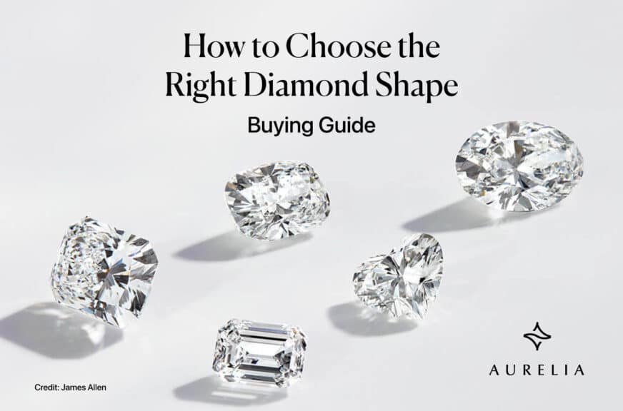 A featured image for an expert buying guide titled "How to Choose the Right Diamond Shape." The image displays five different, high-quality loose diamonds artfully scattered as if they are floating against a clean, bright, neutral background. The featured diamond shapes include some of the most popular and distinct styles: a large Oval cut, a Cushion cut, a Heart shape, a sophisticated Emerald cut, and what appears to be a brilliant Radiant cut. This professional, high-end photograph is designed to instantly showcase the beautiful variety of shapes available, drawing the reader into the comprehensive buying guide. The Aurelia brand logo is subtly placed in the corner.