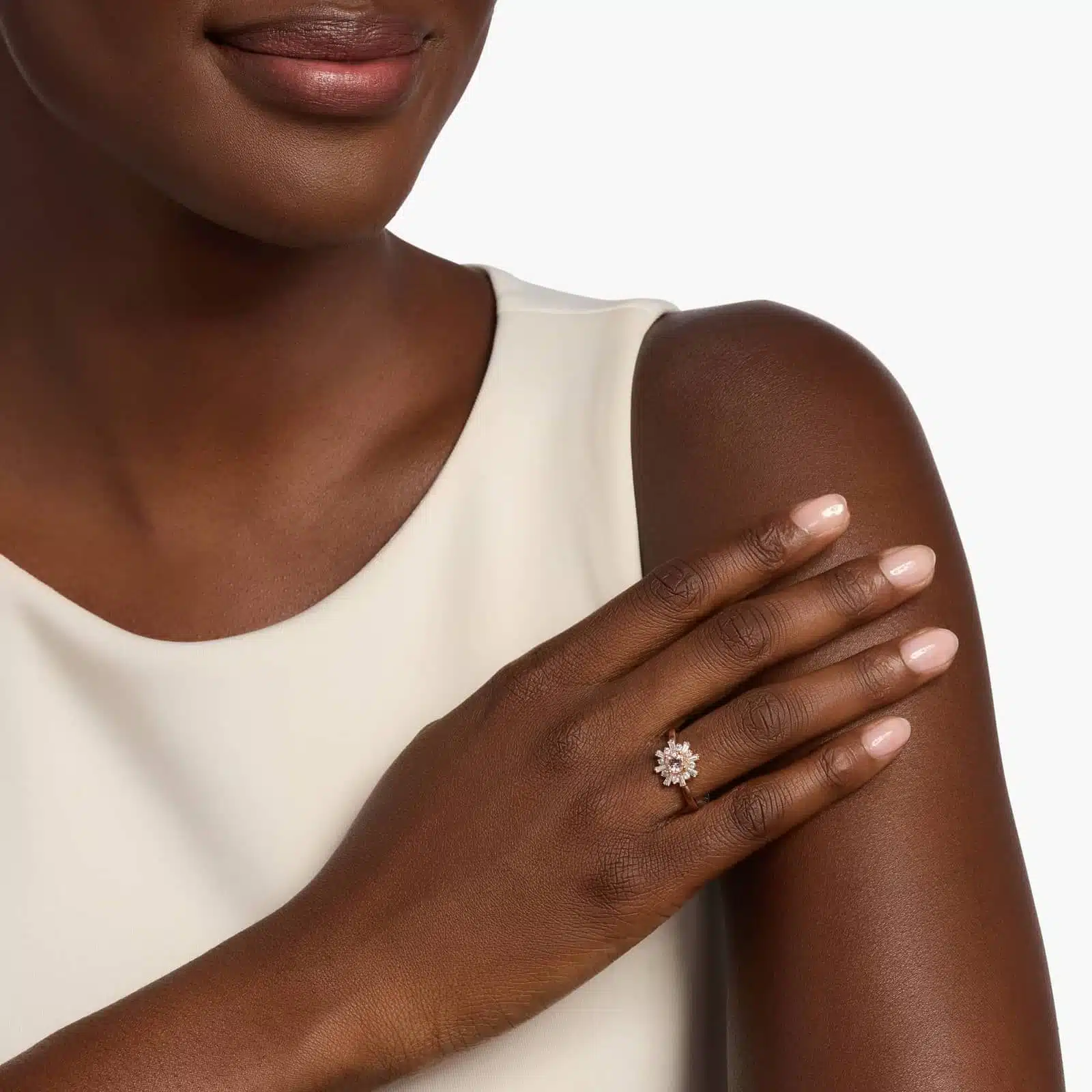 A woman's hand wearing a **Morganite Engagement Ring**, showcasing the round morganite and the unique halo of baguette and round diamonds in 14K rose gold.