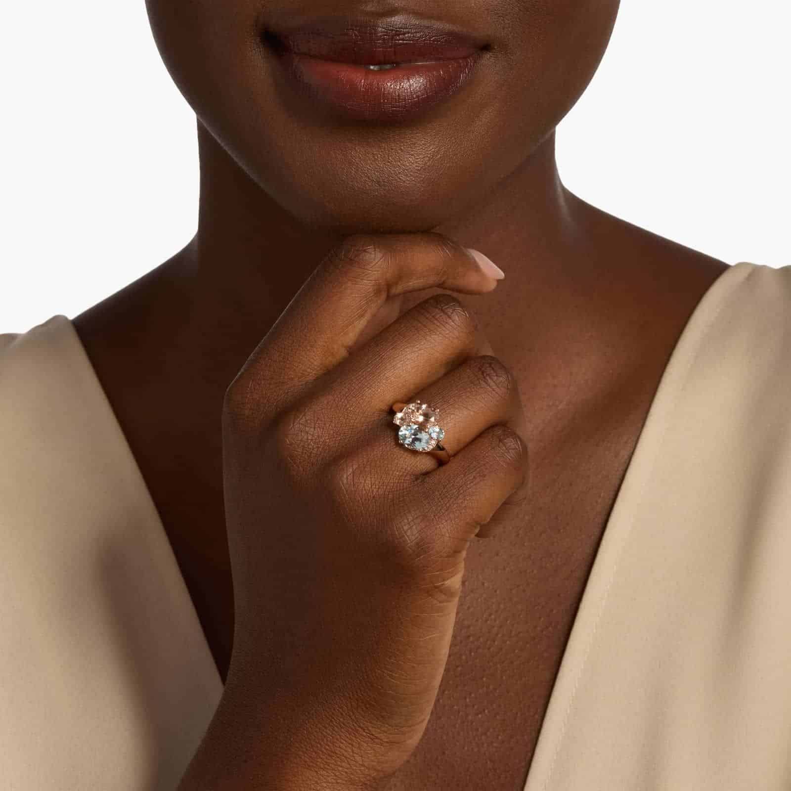 A woman's hand wearing a **Morganite and Aquamarine Engagement Ring**, showcasing the unique combination of pink and blue gemstones in a 14K rose gold setting.