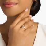 A woman's hand wearing a **Morganite and Diamond Floral Engagement Ring**, showcasing the oval morganite and the beautiful diamond halo in 14K rose gold.