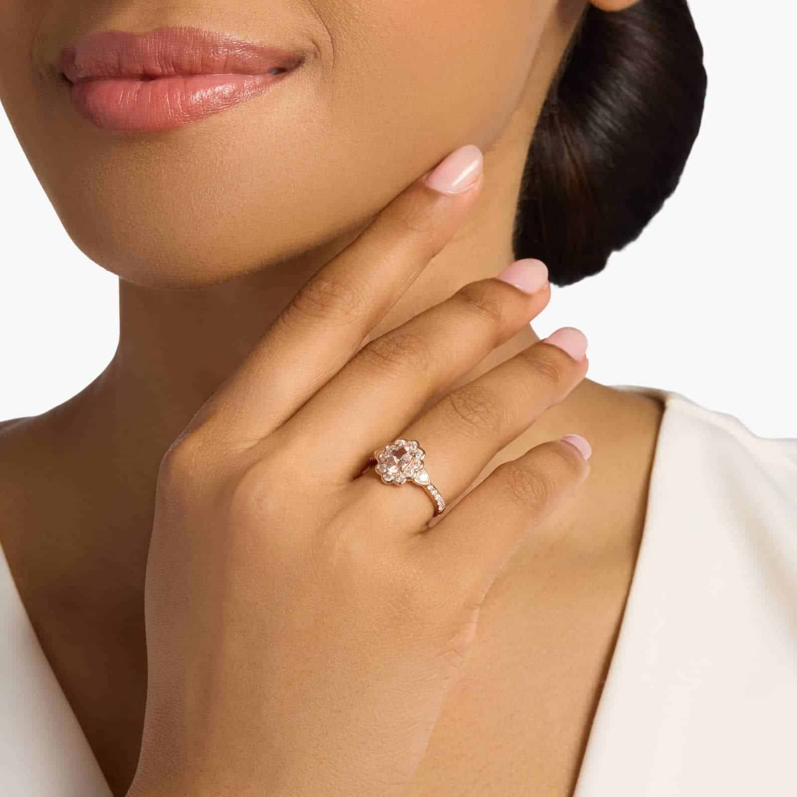 A woman's hand wearing a **Morganite and Diamond Floral Engagement Ring**, showcasing the oval morganite and the beautiful diamond halo in 14K rose gold.