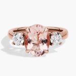 A close-up of a beautiful **Morganite Engagement Ring** on a white background, highlighting the distinct prongs, two round diamond sidestones, and the unique pink color of the 14K rose gold.