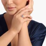 A woman's hand wearing a **Round Morganite Engagement Ring**, showcasing the brilliant round morganite and the surrounding diamond halo in 14K white gold.