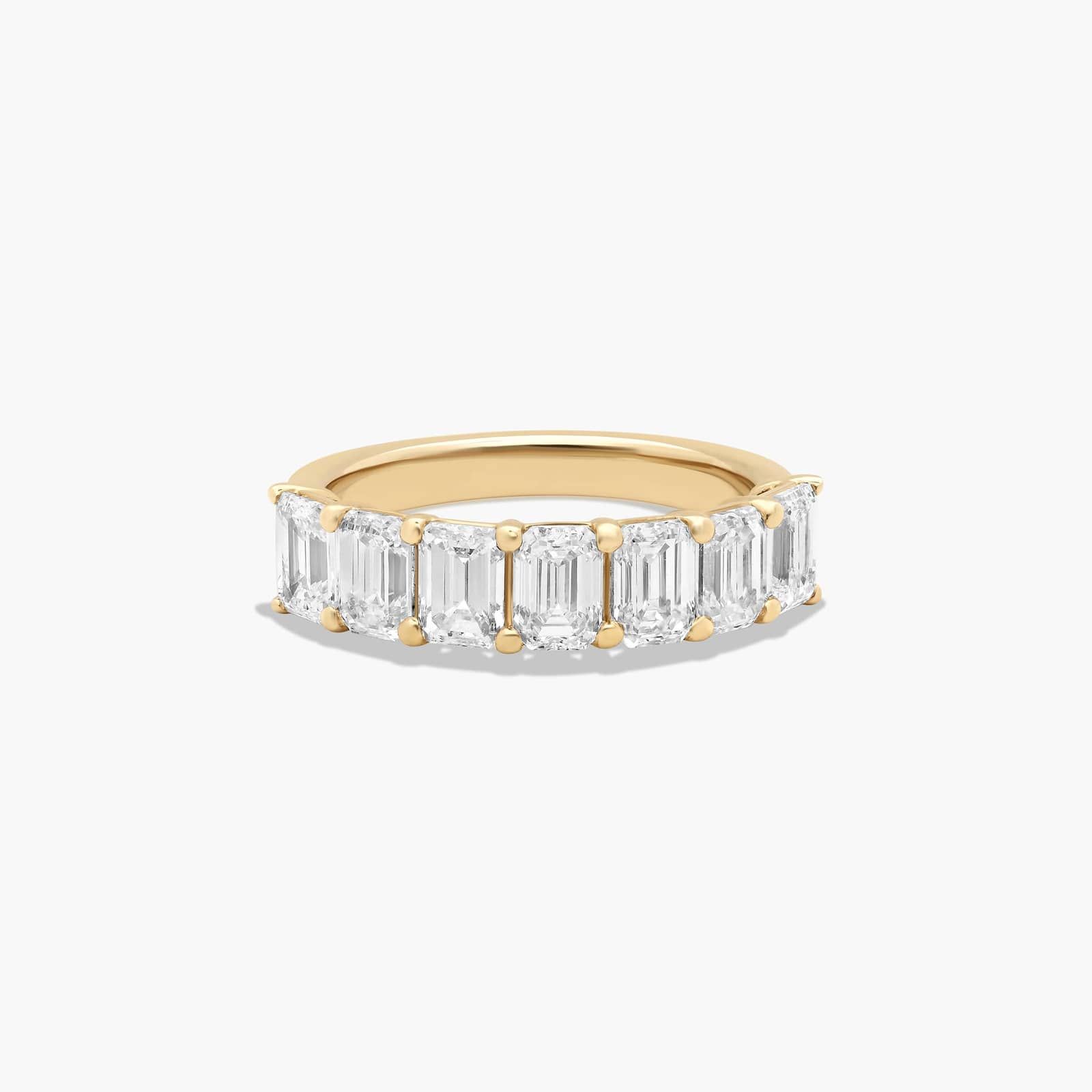 A seven stone emerald cut lab diamond anniversary ring with 2 ctw of stones set in a 14k yellow gold shared prong band, shown on a white background.