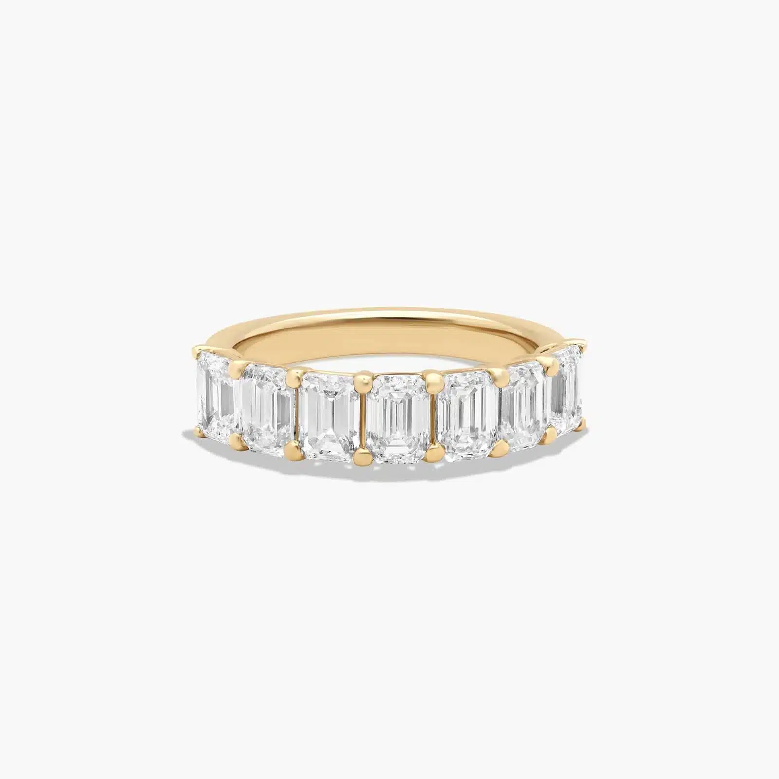 A seven stone emerald cut lab diamond anniversary ring with 2 ctw of stones set in a 14k yellow gold shared prong band, shown on a white background.