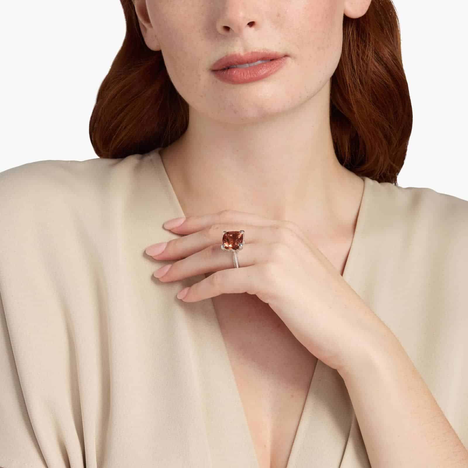 A woman's hand wearing a large **Square Fire Morganite Engagement Ring**, showcasing the impressive 14x14mm cushion-cut morganite and the sparkling pavé diamond band in 18K white gold.