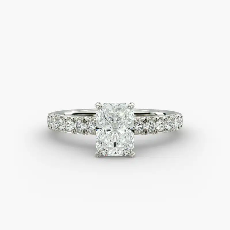 A close-up studio shot of a 3ct radiant cut diamond ring, highlighting the G-VVS2 clarity of the center stone and the intricate pavé setting.