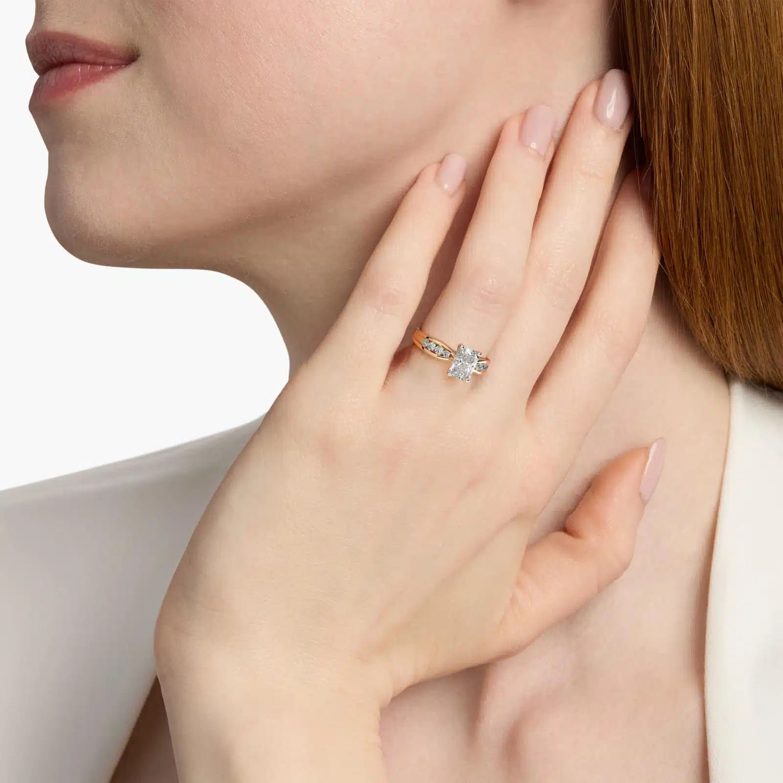 A woman's hand wearing a stunning 2.5 carat radiant cut diamond ring, showcasing the D-VS2 center stone and a yellow gold Bow-Tie band.