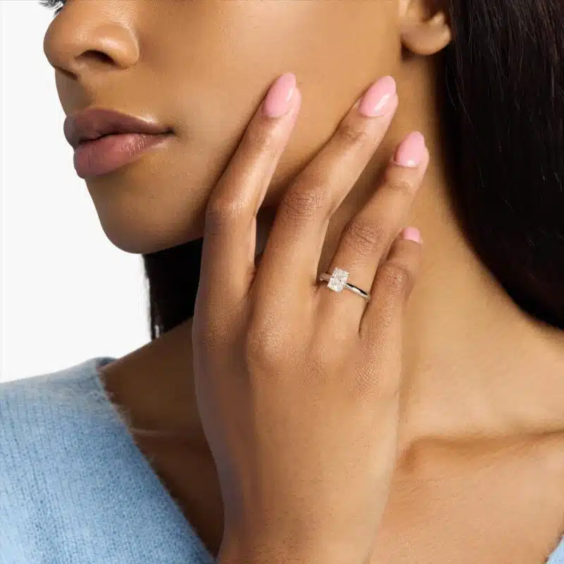 A woman's hand wearing a massive 4 carat radiant cut diamond ring with a D-VVS1 lab-grown center stone in a white gold Tapered Cathedral setting.