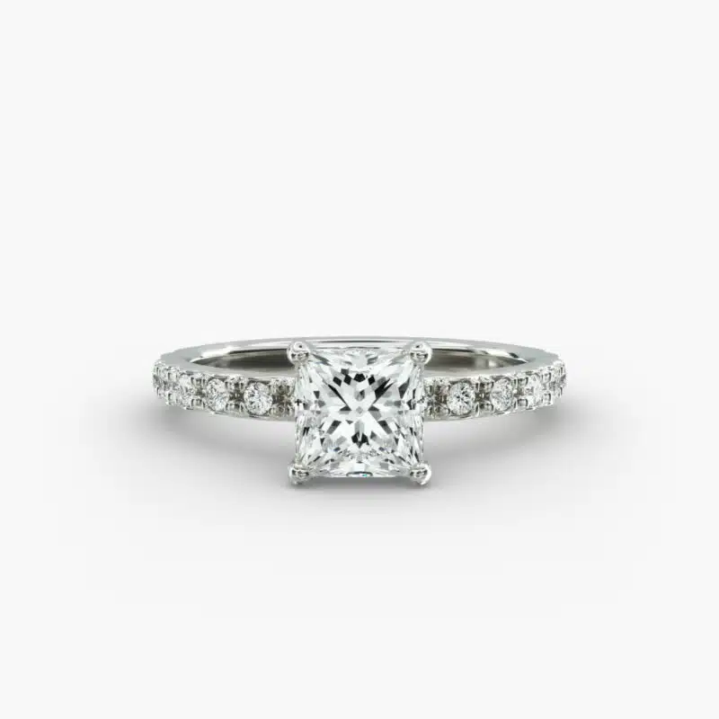 A close-up studio shot of a **7 carat diamond ring**, highlighting the sharp corners of the Princess cut diamond and the delicate detail of the French pavé side stones.