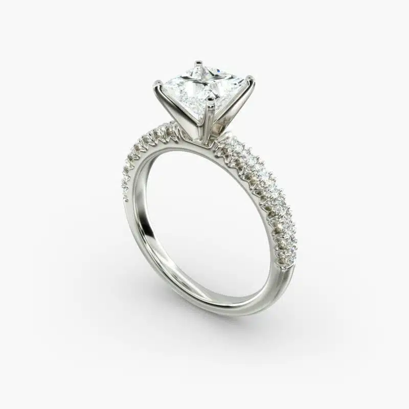 A close-up side view of a 2 carat princess cut diamond engagement ring, highlighting the F-VVS1 clarity of the center stone and the detailed French pavé setting.