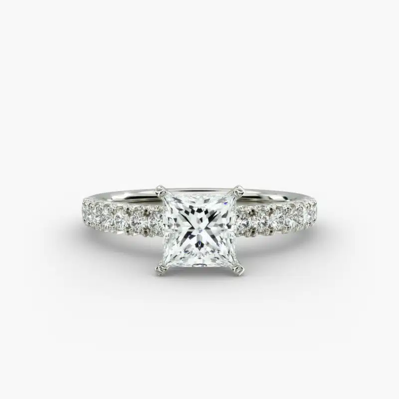 A close-up side view of a 2 carat princess cut diamond engagement ring, highlighting the F-VVS1 clarity of the center stone and the detailed French pavé setting.