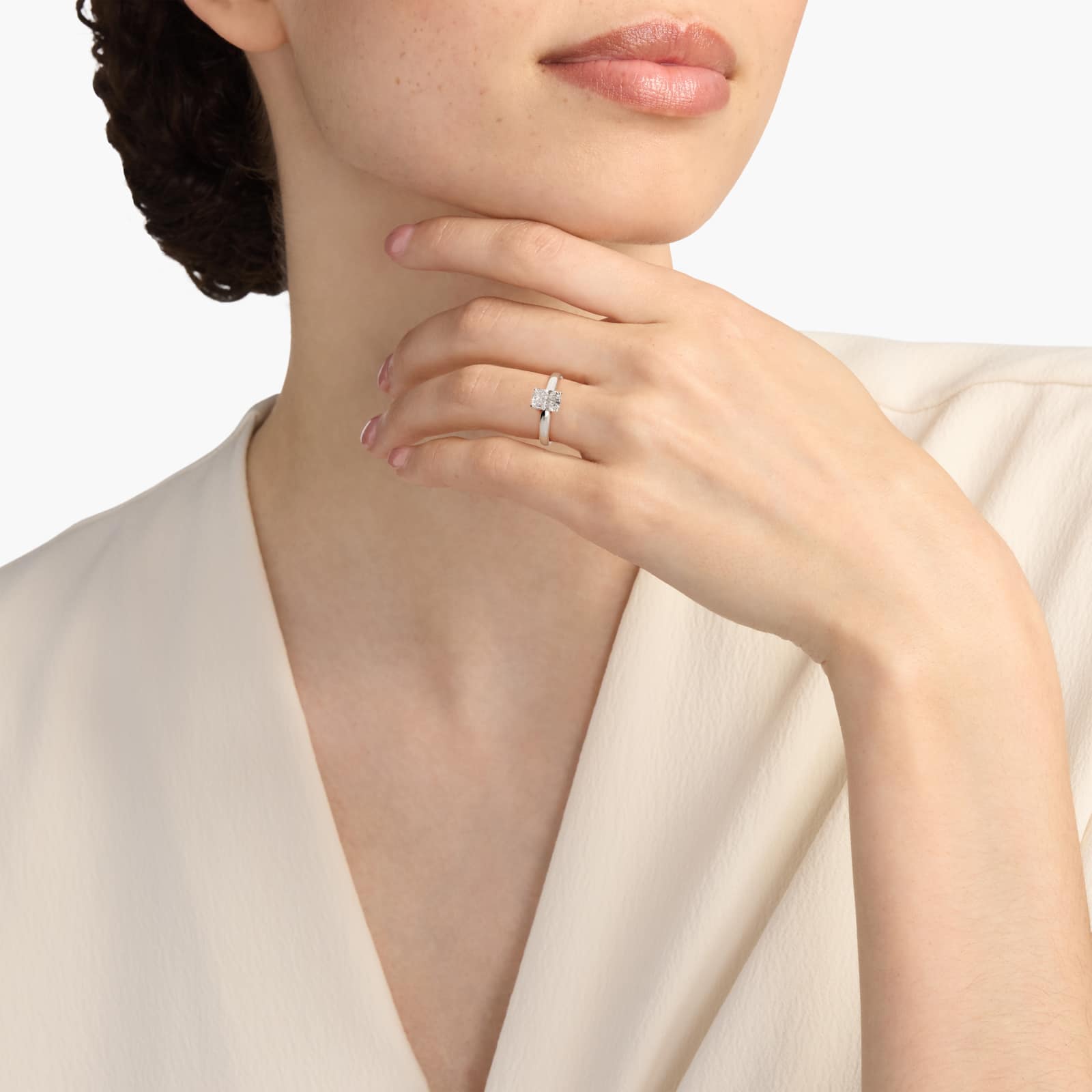 A hand wearing a massive 5 carat radiant cut natural diamond ring with an H-VS2 center stone in a classic platinum solitaire setting.