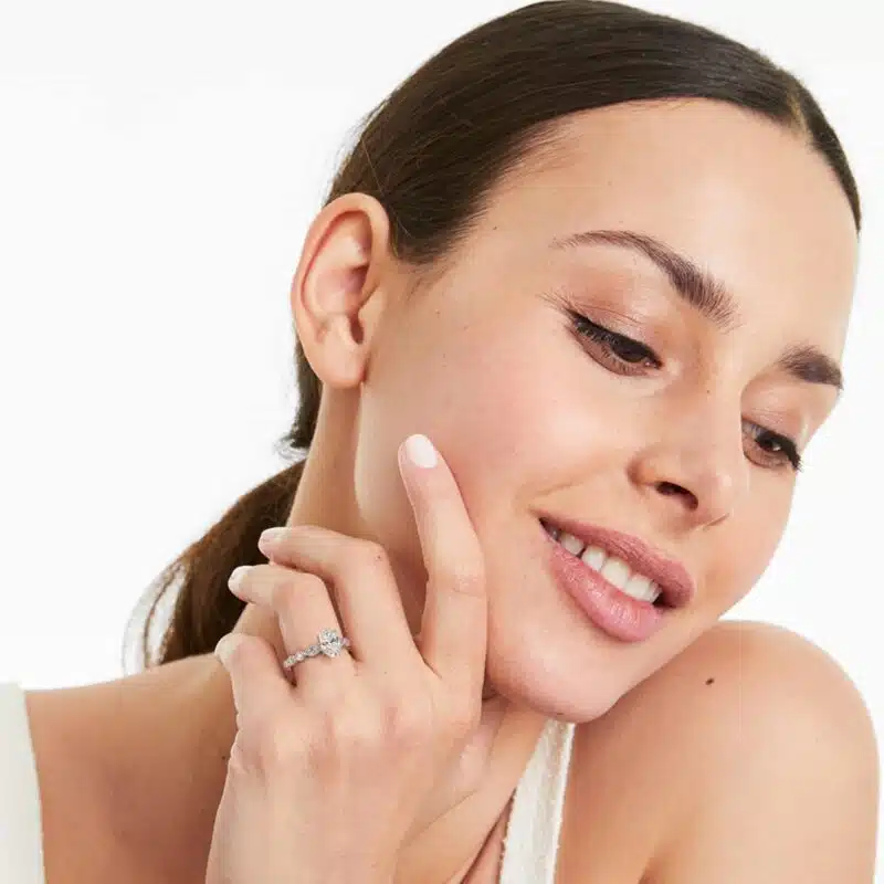 A woman's hand wearing a majestic 7 carat diamond ring showcasing the large oval diamond and the delicate marquise side stones in a platinum setting.