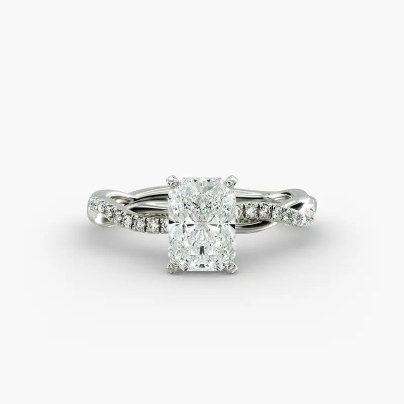 A close-up side view of a 2 carat radiant cut diamond ring, highlighting the F-VS1 clarity of the center stone and the elegant twist setting.