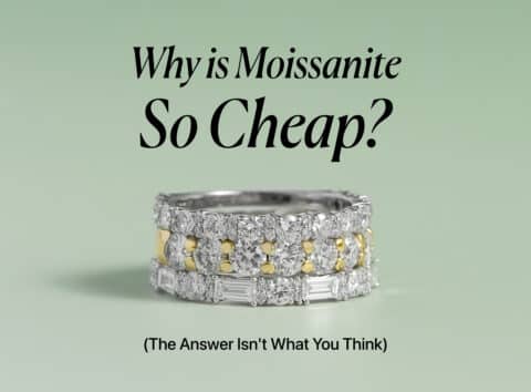 An elegant image showing three stacked rings with glittering moissanite gems on a pale green background. The top ring is a simple band of round stones, the middle ring alternates between round stones and yellow-gold sections, and the bottom ring features baguette-cut stones. The title "Why is Moissanite So Cheap?" is centered above the rings with the subtitle "(The Answer Isn't What You Think)" below them.