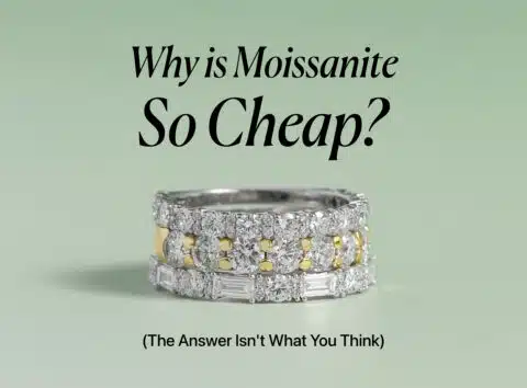 An elegant image showing three stacked rings with glittering moissanite gems on a pale green background. The top ring is a simple band of round stones, the middle ring alternates between round stones and yellow-gold sections, and the bottom ring features baguette-cut stones. The title "Why is Moissanite So Cheap?" is centered above the rings with the subtitle "(The Answer Isn't What You Think)" below them.