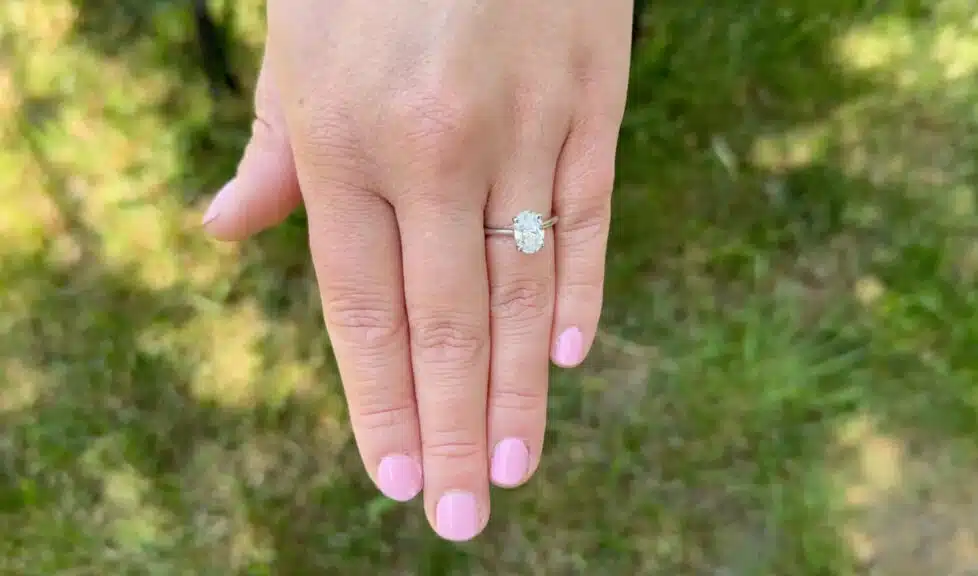 The Blue Nile oval lab-grown diamond ring worn on a finger outdoors, showing how it looks in natural lighting.