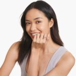 A woman's hand wearing a massive marquise solitaire diamond engagement ring with a 7.00 ct. lab-grown center stone in a 14K yellow gold setting.