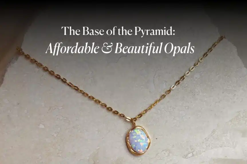 A gold chain necklace with a beautiful, affordable white opal pendant on a light stone surface. The image is titled 'The Base of the Pyramid: Affordable & Beautiful Opals'.