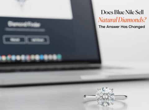 A 2-carat platinum solitaire engagement ring in sharp focus with a laptop displaying the Blue Nile Diamond Finder in the background. Text overlay asks, "Does Blue Nile Sell Natural Diamonds?"