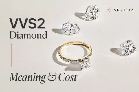 An 18k yellow gold solitaire engagement ring set with a VVS2 diamond, with several loose VVS2 diamonds scattered on a white background.
