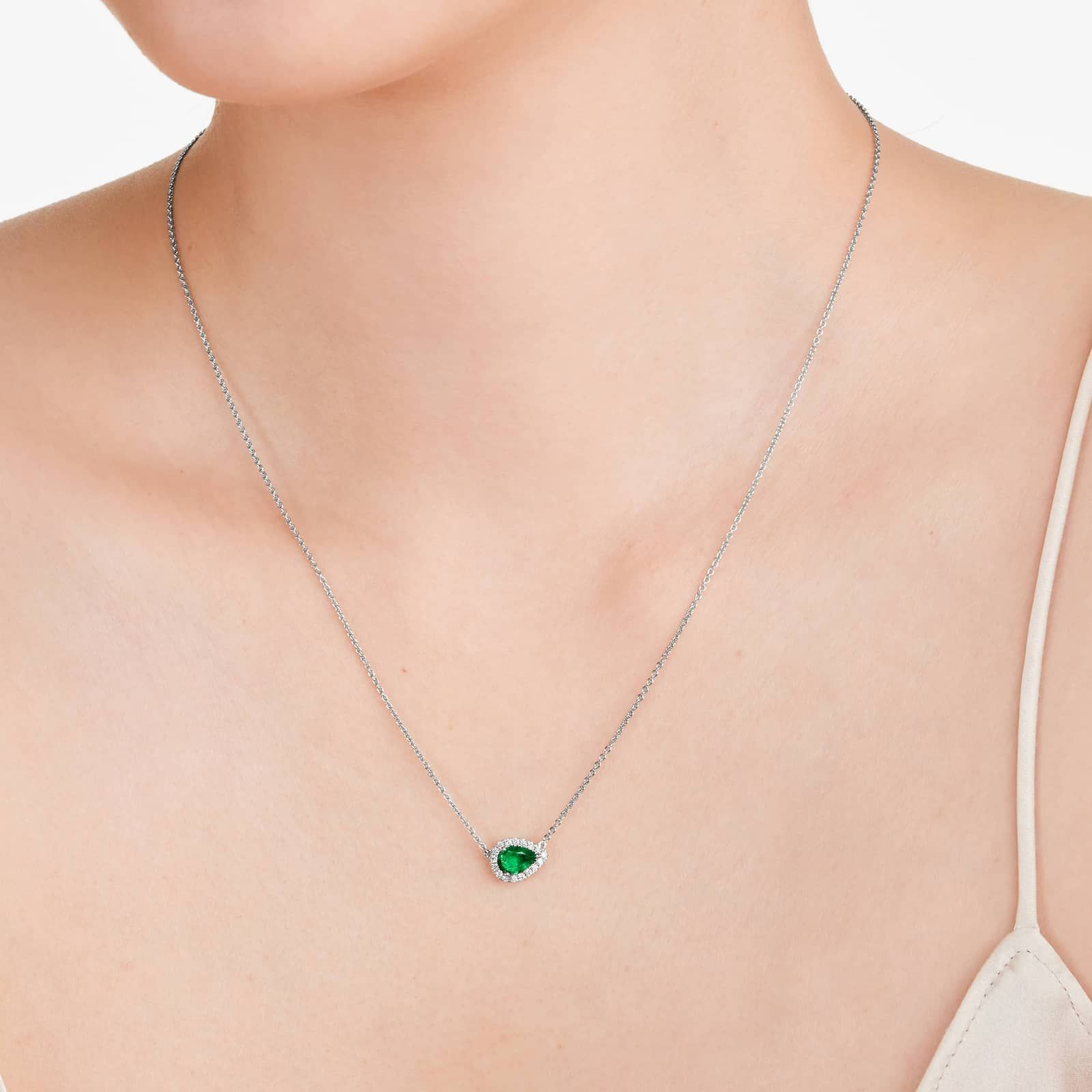 An East-West Pear Emerald (0.65 CT min) and Diamond Halo Necklace (0.14 CTW) in 18K White Gold, a modern and high-quality option among Luxury Push Present Ideas.