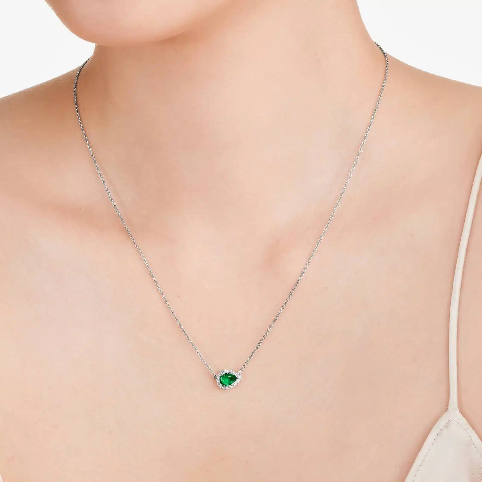 An East-West Pear Emerald (0.65 CT min) and Diamond Halo Necklace (0.14 CTW) in 18K White Gold, a modern and high-quality option among Luxury Push Present Ideas.
