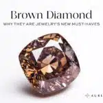 A large, rich cognac brown cushion-cut diamond with high saturation and brilliance, placed on a white background. Title text reads: Brown Diamond - Why They Are Jewelry's New Must-Haves.