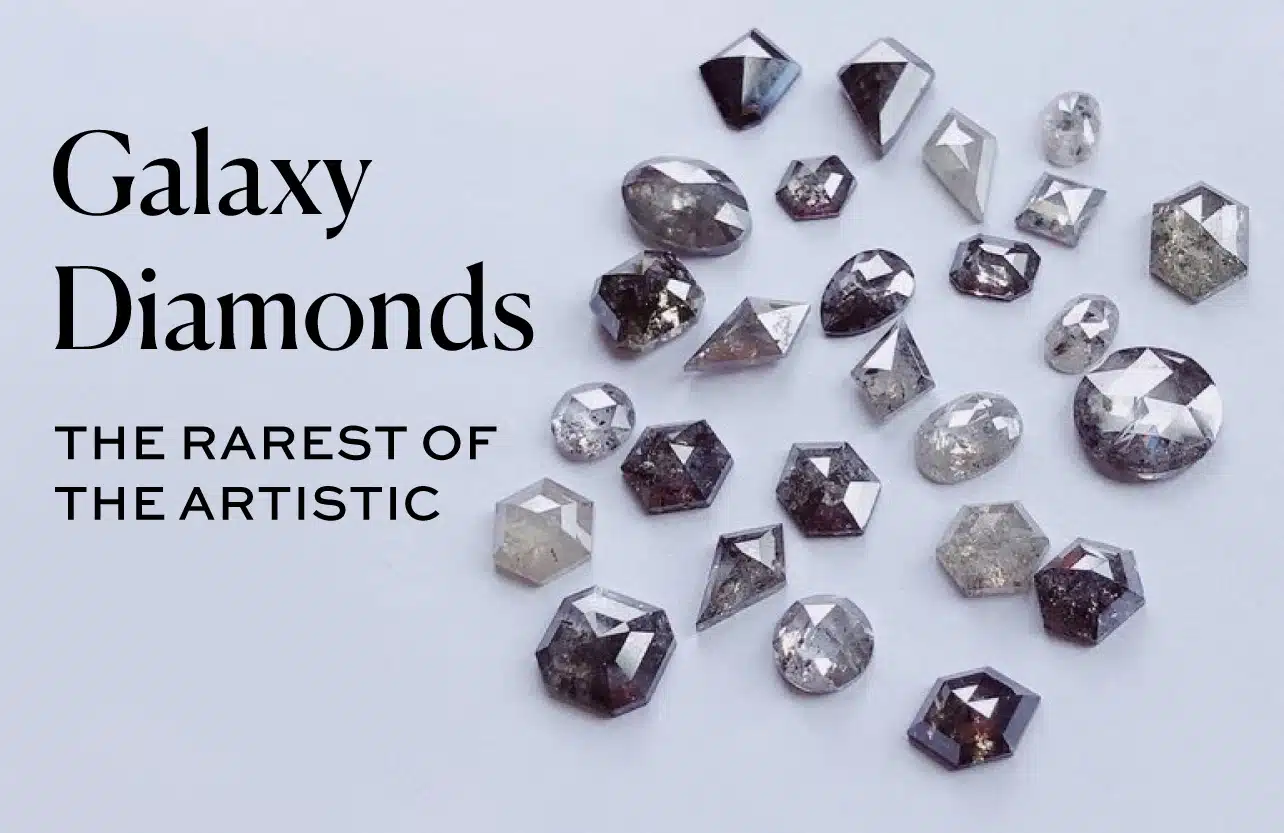 A collection of rough and geometric-cut Galaxy Diamonds, featuring very dark gray to black body color and a dense field of reflective inclusions that resemble a starry night sky. This illustrates the rarest and most dramatic type of artistic included gray diamond.