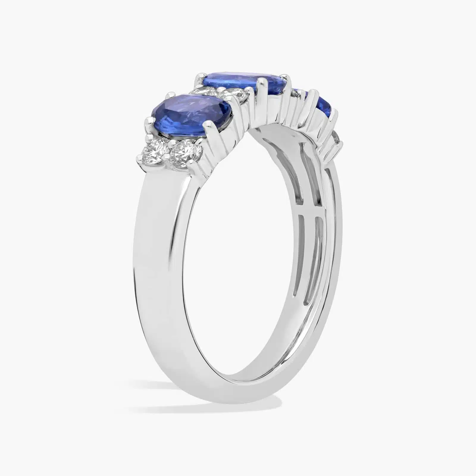 A 14K White Gold 3 Stone Diamond Rings With Sapphires ring (3.60 mm wide) featuring three Oval Blue Sapphires set in prongs, accented by 0.31 CTW Round Diamonds on the shank.