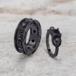 A set of Black Wedding Ring Sets His and Hers featuring a Princess Cut Black Moissanite Skull Engagement Ring and matching wedding band in 925 Sterling Silver with a Gun Metal finish.