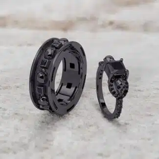 A set of Black Wedding Ring Sets His and Hers featuring a Princess Cut Black Moissanite Skull Engagement Ring and matching wedding band in 925 Sterling Silver with a Gun Metal finish.
