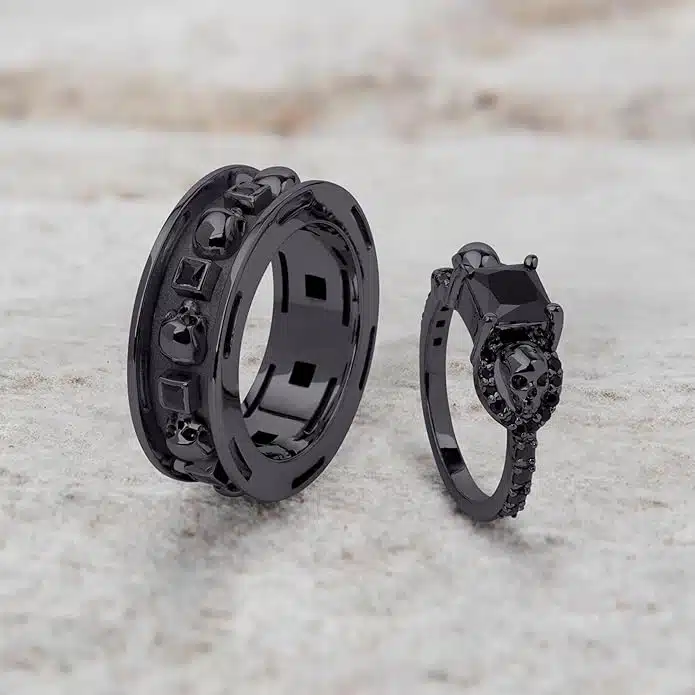 A set of Black Wedding Ring Sets His and Hers featuring a Princess Cut Black Moissanite Skull Engagement Ring and matching wedding band in 925 Sterling Silver with a Gun Metal finish.