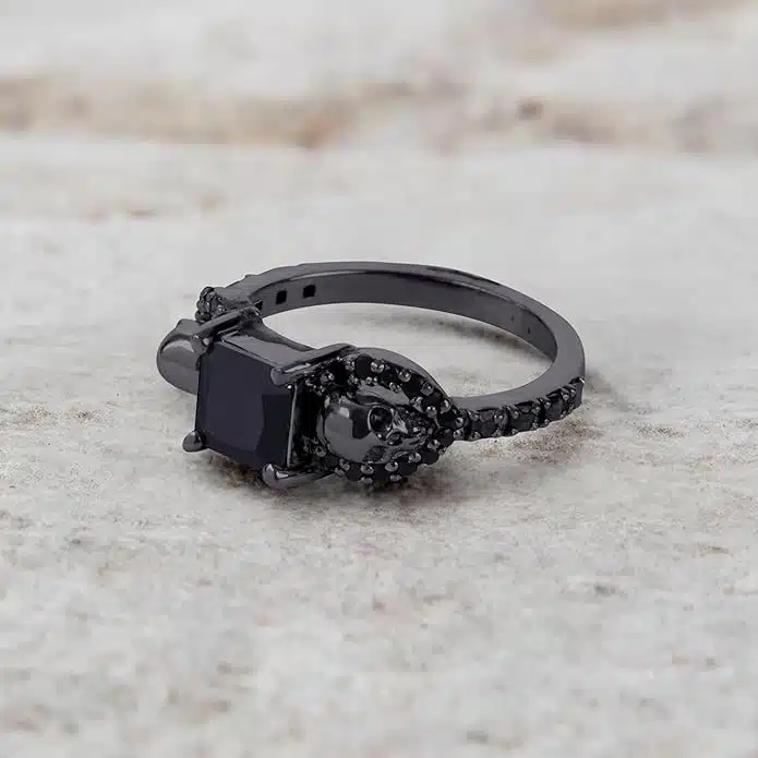 A set of Black Wedding Ring Sets His and Hers featuring a Princess Cut Black Moissanite Skull Engagement Ring and matching wedding band in 925 Sterling Silver with a Gun Metal finish.