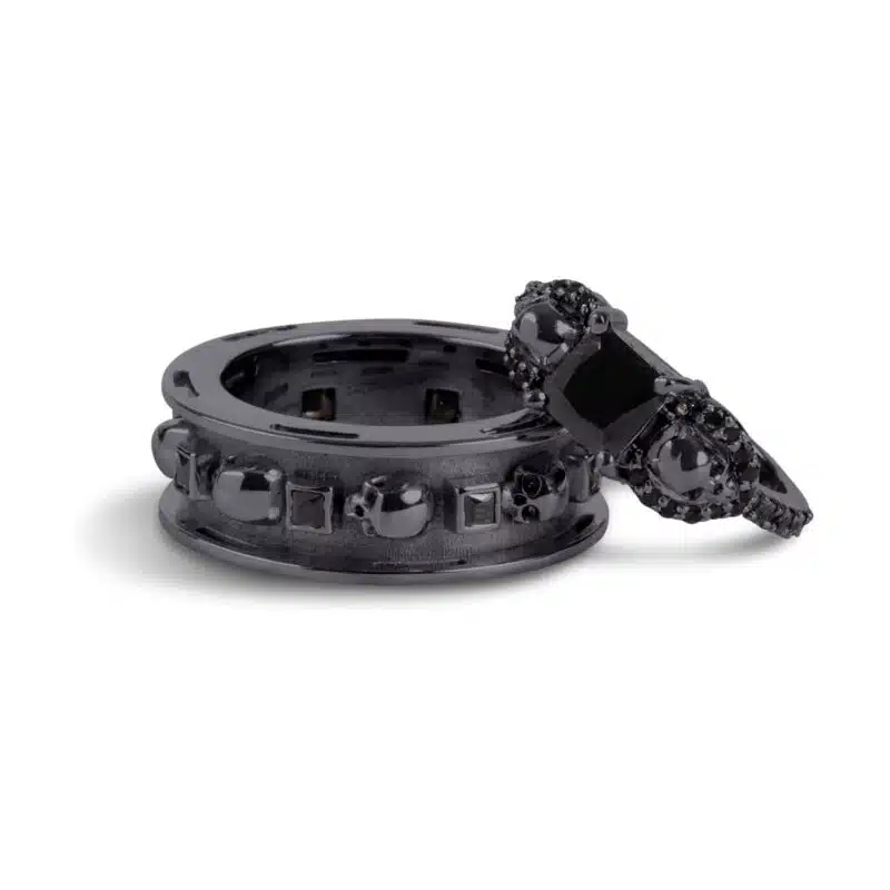 A set of Black Wedding Ring Sets His and Hers featuring a Princess Cut Black Moissanite Skull Engagement Ring and matching wedding band in 925 Sterling Silver with a Gun Metal finish.