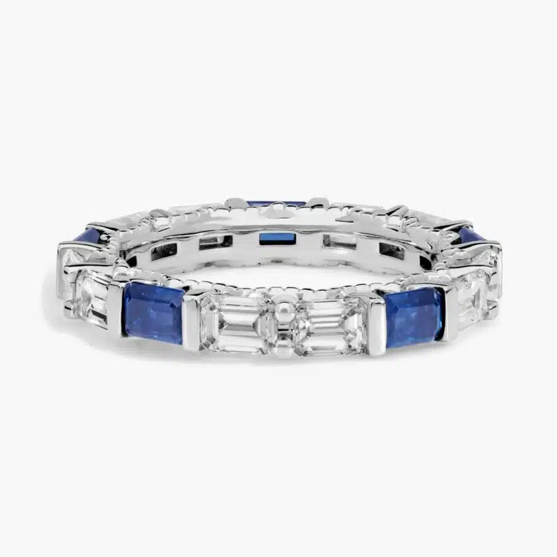An Alternating East-West Emerald Cut Sapphire and Diamond Blue Wedding Rings For Women band (3.30mm) in 14K White Gold with over 2.5 CTW of stones.
