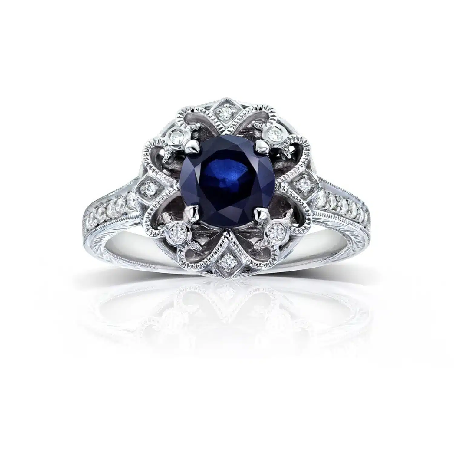 A 14K White Gold Antique Style Vintage Art Deco Sapphire Rings engagement ring featuring a 1.3 Carat Round Blue Sapphire center stone, a Floral Design, and a 1/5 CTW Pave set diamond halo.