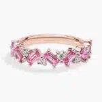 A 14K Rose Gold and Pink Sapphire Ring featuring 7 Baguette Pink Sapphires and 6 Round Diamonds (0.18 CTW) set in prongs, creating a romantic, emerald-style look on a 2.50 mm band.