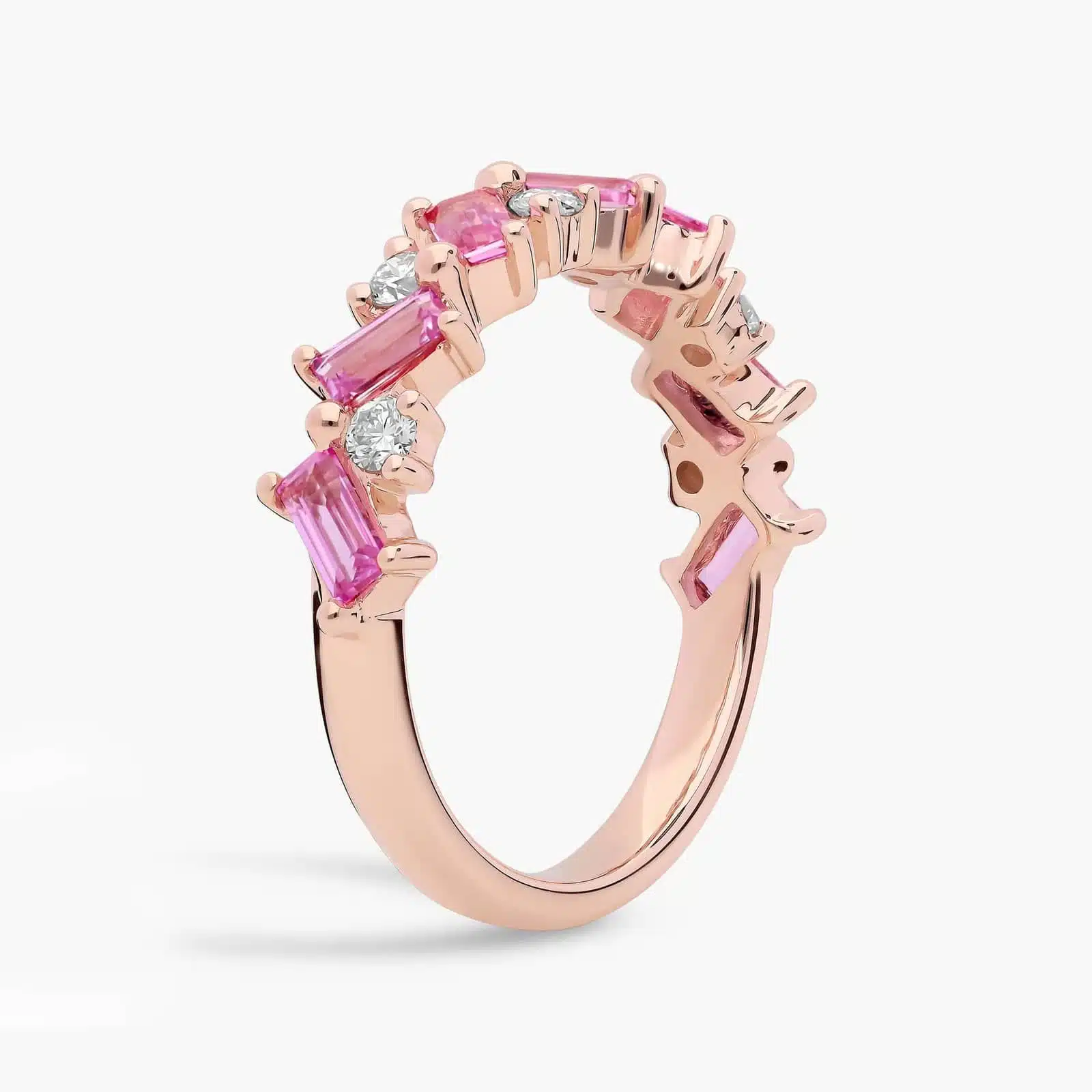 A 14K Rose Gold and Pink Sapphire Ring featuring 7 Baguette Pink Sapphires and 6 Round Diamonds (0.18 CTW) set in prongs, creating a romantic, emerald-style look on a 2.50 mm band.