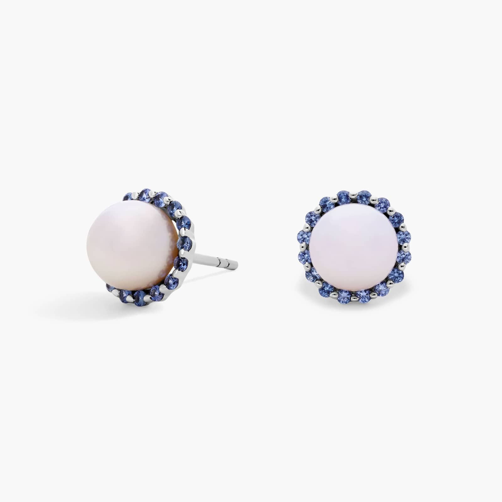 A pair of 14K White Gold Pearl and Sapphire Drop Earrings (Halo Stud style) featuring 7 mm Freshwater Cultured Pearls surrounded by a halo of 32 Round Blue Sapphires, secured with Push Backs.