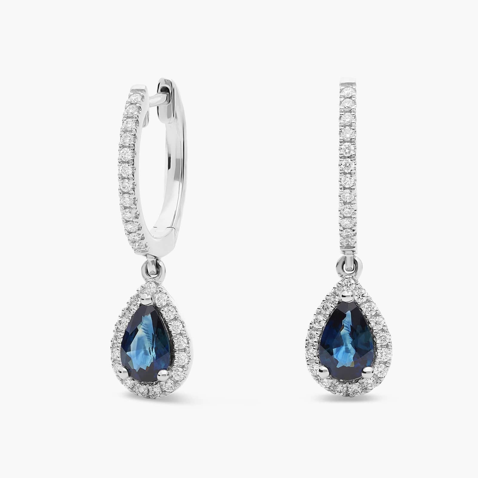 halo-pear-sapphire-and-diamond-dangle-earrings-14k-1-22-ctw A pair of 14K White Gold Sapphire and Diamond Dangle Earrings featuring two 6x4 mm Pear Shaped Blue Sapphires (1 CT total) and a 0.22 CTW Round Diamond Halo, secured with Hinged Snap Backs.