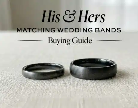 Black and gunmetal finish his and hers matching wedding bands (one narrow, one wide) on a beige linen surface, illustrating a guide to coordinating rings.