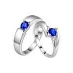 A set of Blue Wedding Ring Sets His and Hers in 14K White Gold featuring an Oval Blue Sapphire Halo engagement ring and a coordinating men's band.
